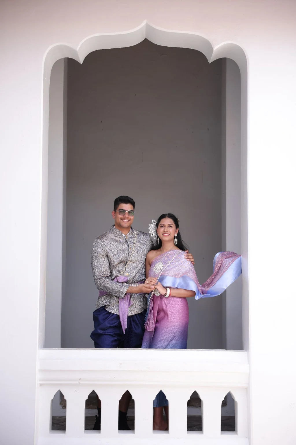 Malika and Jyanesh standing together in a white ornamental archway